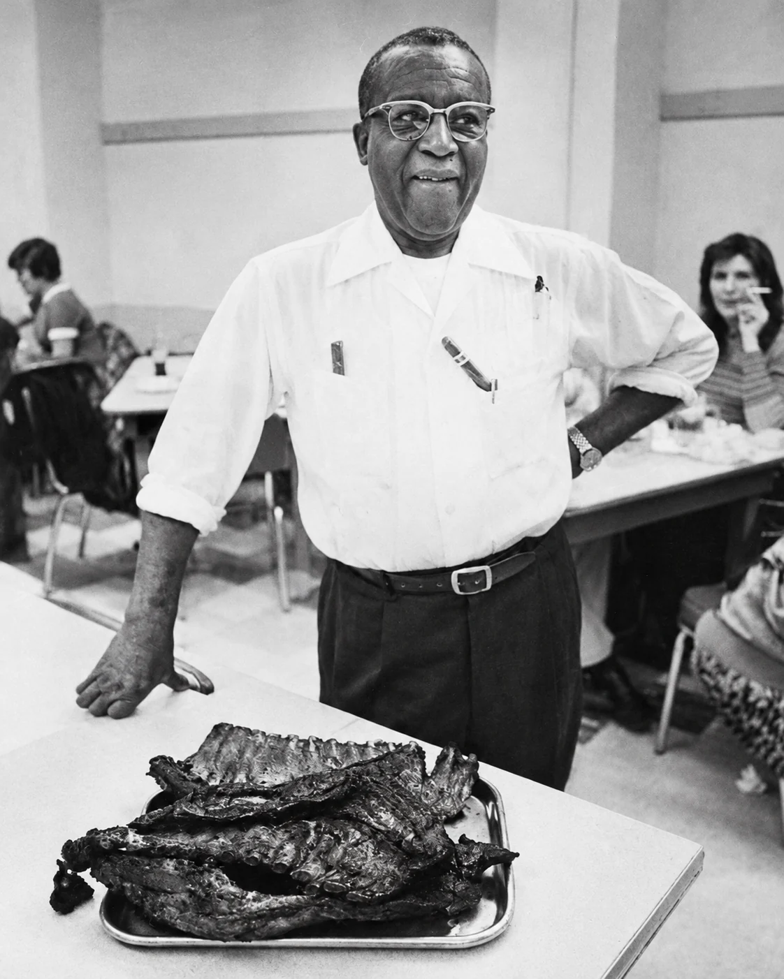 Arthur Bryant standing beside a tray of ribs in his restaurant, circa 1972