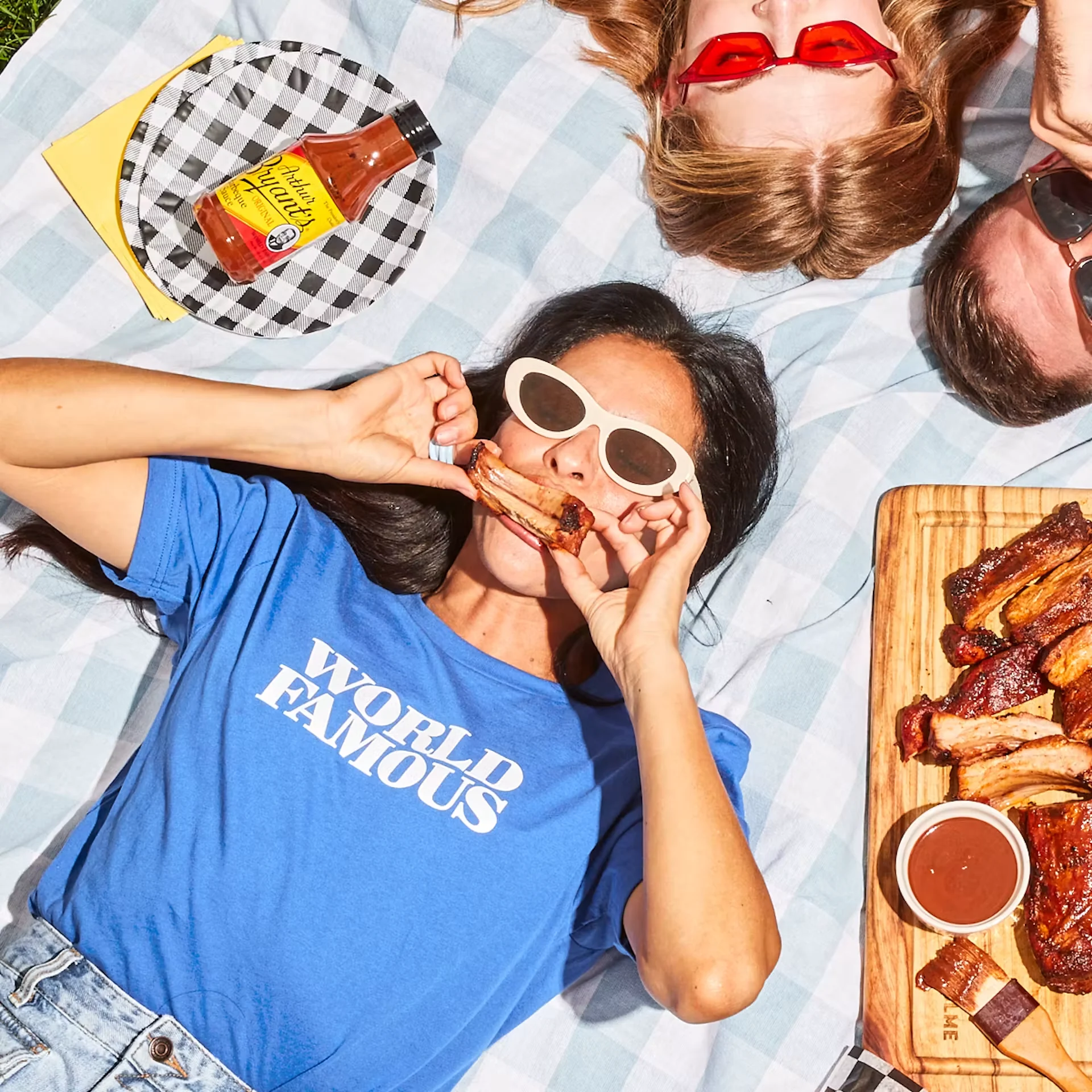 A guest wearing a blue World Famous T-shirt and enjoying Arthur Bryant’s ribs